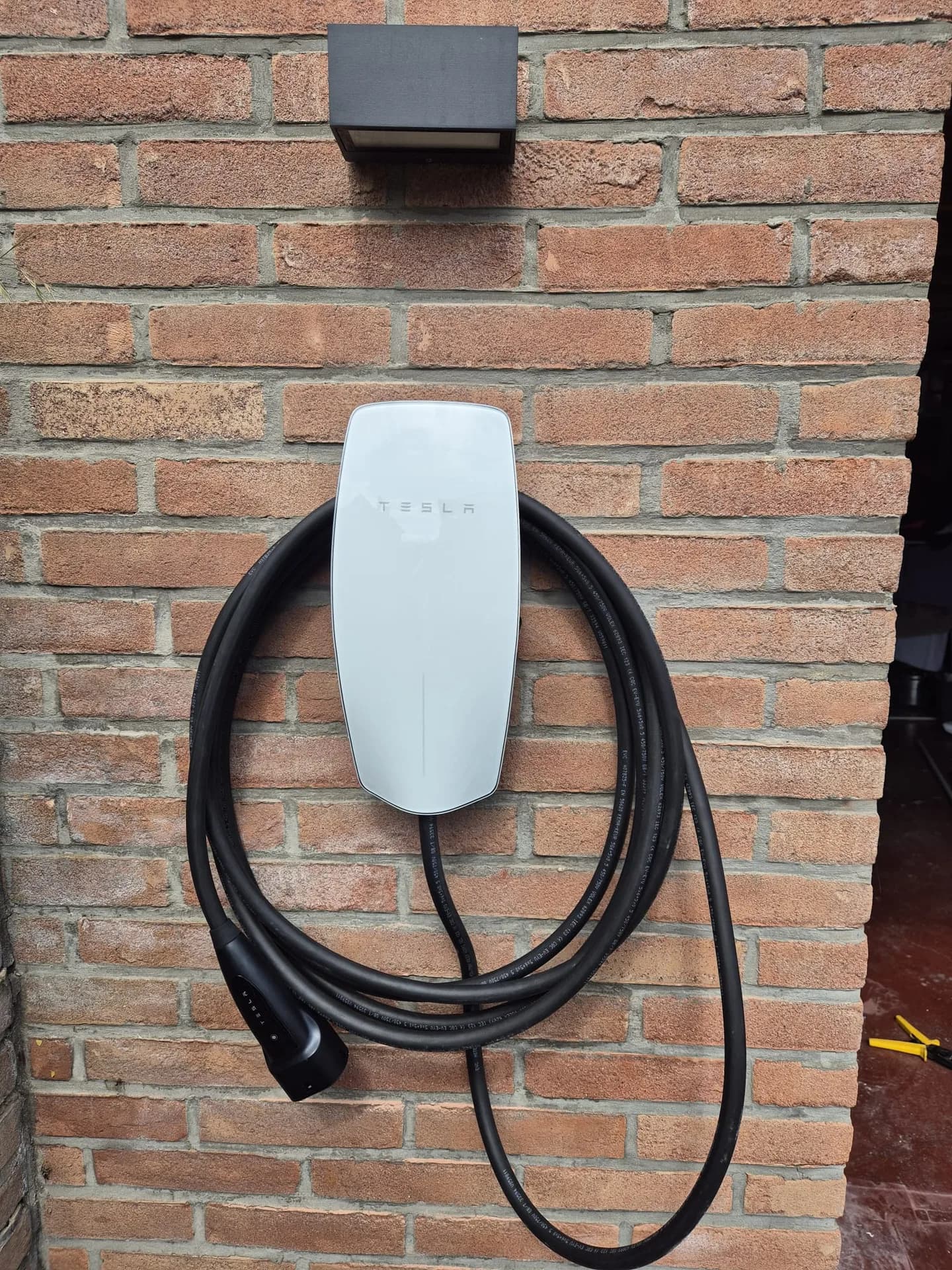 Borne de recharge posée par Belix sur un mur de briques.