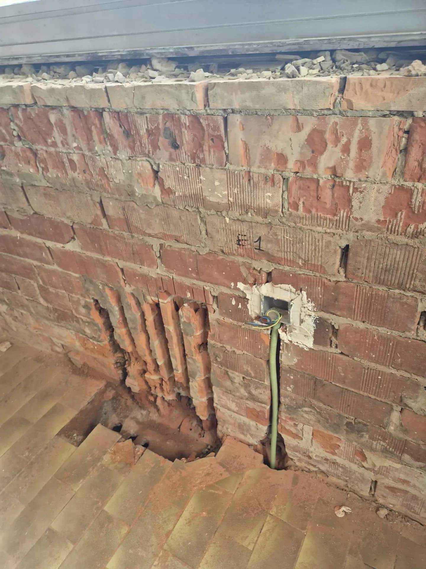 Anciens conduits dans un mur en brique, à côté d'une nouvelle gaine.