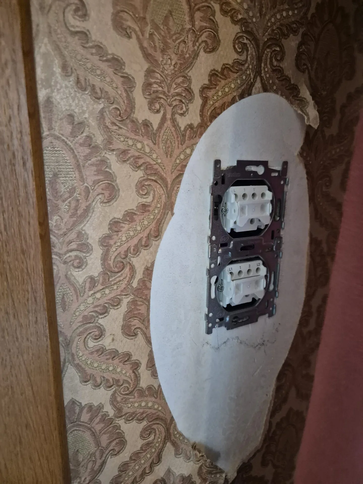Boîtier double posé dans un mur au papier peint d'époque.
